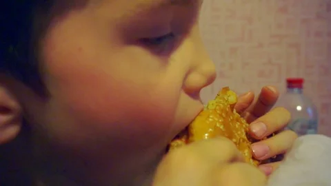 Boy eagerly eats a burger cooked at home.close-up portrait Stock Footage 89225922