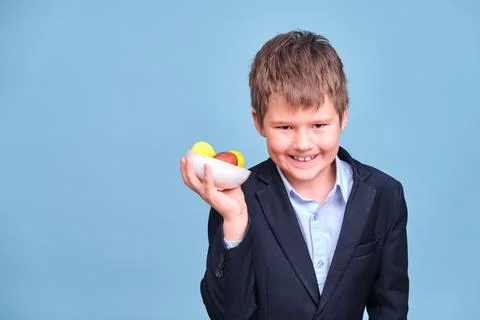 A boy with Easter colored eggs in his hands, copy space on a blue studio back Stock Photos