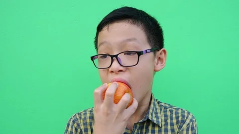 Boy eating an apple in front of green screen Stock Footage 88935062