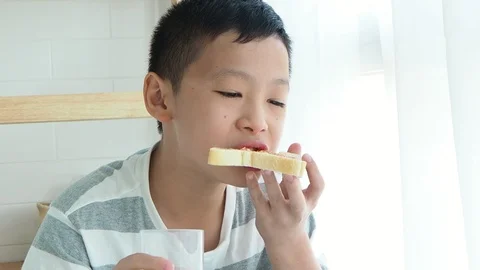 Boy eating bread and drinking milk at home Stock Footage 88898079