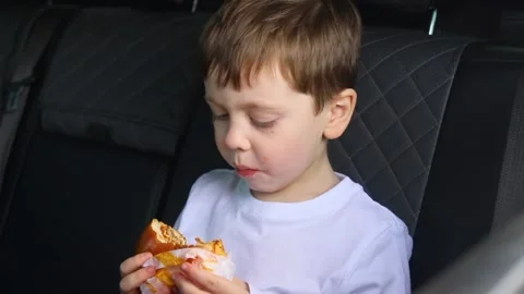 The boy is eating a burger . An article about fast food. Junk food. Stock Footage 203288953