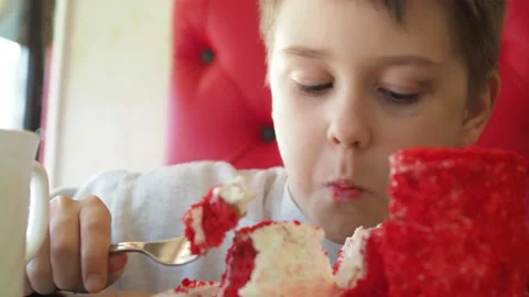 A boy is eating a cake with a fork in a cafe. Emotions of surprise, happiness on Stock Footage 154153335