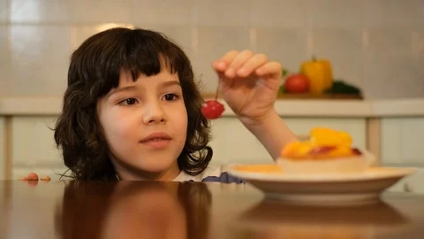 Boy eating cherry from top of cake, kid stealing red cherry from cake Stock Footage 125706715