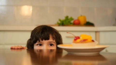 Boy eating cherry from top of cake, kid stealing red cherry from cake Stock Footage 125707046