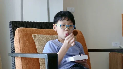 Boy eating cookie on chair Stock Footage 75596284