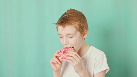 Boy eating donuts on the green background Stock Footage 232810124