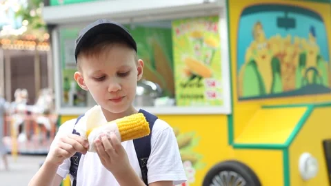 Boy eating fresh boiled corn on street market food track Stock Footage 157262113
