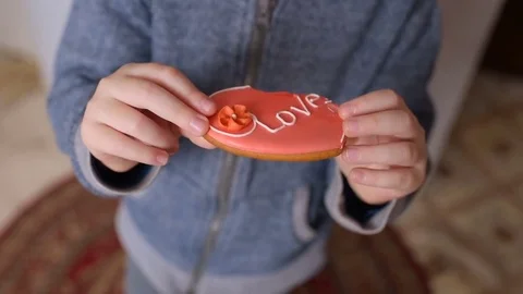 Boy eating a gingerbread in the shape of a heart with the inscription "love" Stock-Footage 85261849