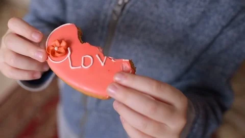 Boy eating a gingerbread in the shape of a heart with the inscription "love" Stock Footage 85261927