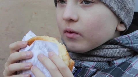 Boy eating hamburger in winter Stock-Footage 296374446