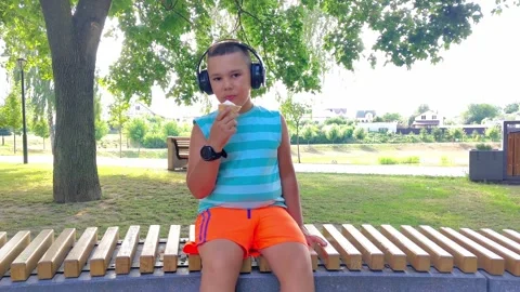Boy Eating Ice Cream Sitting Outdoors in Park Video stock 342589336