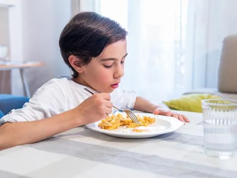 Boy eating meal at table Stock Photos