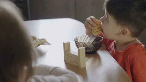 Boy eating morning pancakes while playing with wooden blocks. Smiling happy Video stock 202022286