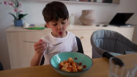 Boy eating potato gnocchi with fork during family meal, enjoying homemade f.. Vídeos de archivo 340968412