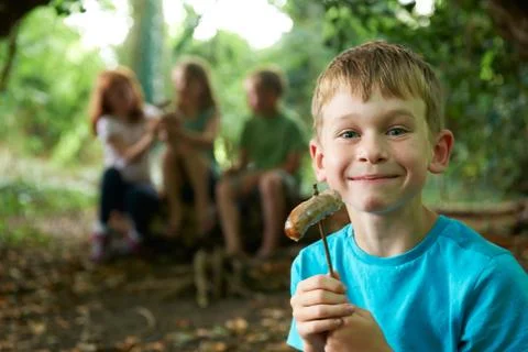 Boy Eating Sausage Around Camp With Friends Stock Photos
