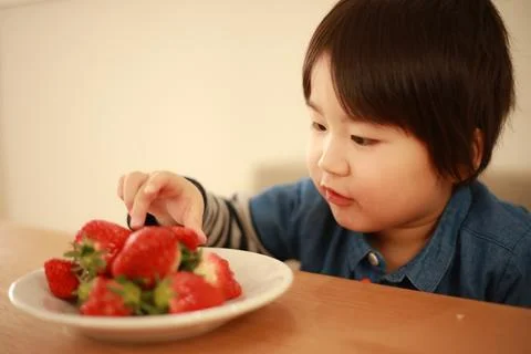 Boy eating strawberries Stock Photos
