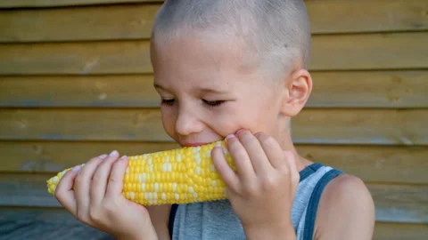 A boy is eating sweet boiled corn outside. Stock Footage 330247942
