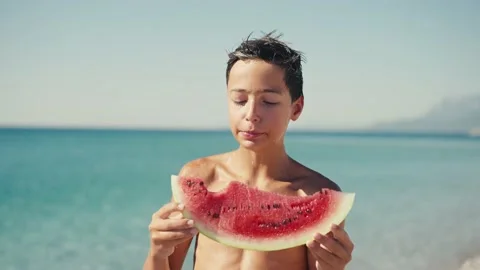 Boy eating watermelon on the beach, summertime Видео 200657551