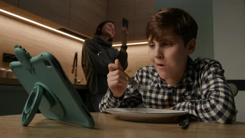Boy Eating While Watching Tablet, Mom on Video Call Stock Footage 295113356
