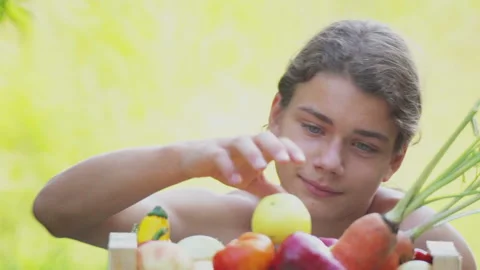 A boy eats an apple and considers fresh vegetables. Stock Footage 114251390