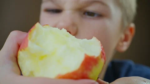 A boy eats an apple, a healthy, natural fruit. Video stock 295317018