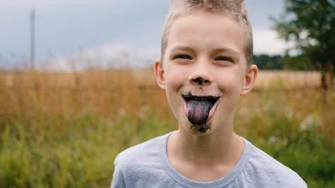 The boy eats black ice cream. Slow motion. Stockbeeldmateriaal 121205473