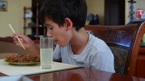 The boy eats buckwheat noodles with chopsticks. 4k. Slow-motion shooting. Stock Footage 78813847
