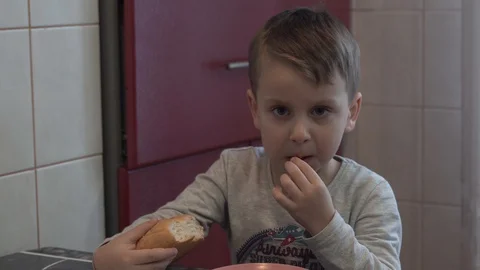 The boy eats a bun in the kitchen. Stock Footage 125177160