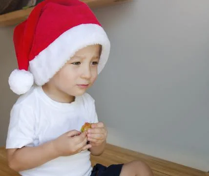 A boy eats candy in a Christmas hat. Stock Photos