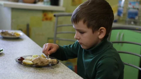 Boy eats chicken while sitting at the table Stock Footage 118324951