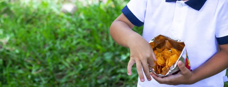 A boy eats chips in the park. Selective focus Stock Photos