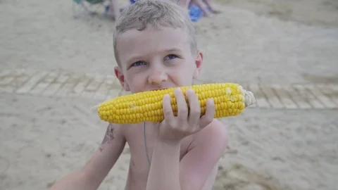 The boy eats corn smiling at camera. Slowmotion Stock Footage 94224231