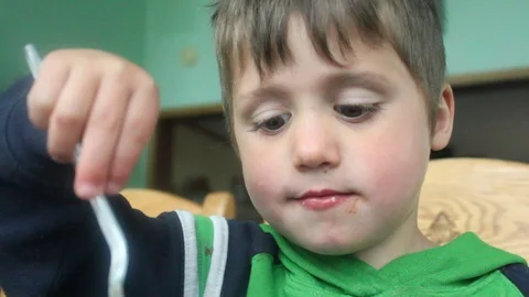 Boy eats with fork and hands Stock Footage 107799129