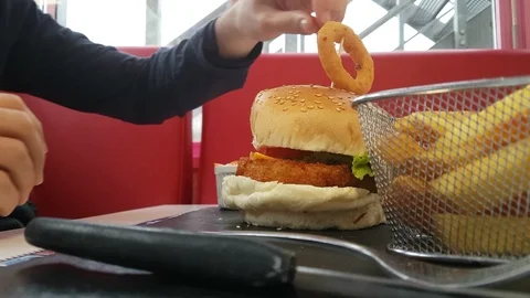 Boy eats hamburger in a typical american restaurant - vegan burgers Stock-Footage 98657682