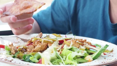 Boy eats healthy lunch of green salad with vegetables and nuts in a cafe Stock Footage 271089729