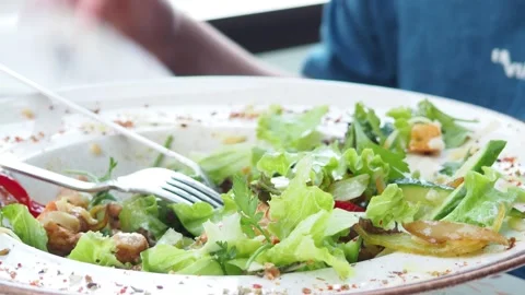 Boy eats healthy lunch of green salad with vegetables and nuts in a cafe Stock Footage 271089814