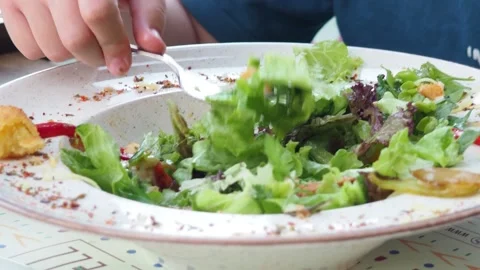 Boy eats healthy lunch of green salad with vegetables and nuts in a cafe. Diet.  Stock Footage 271089907