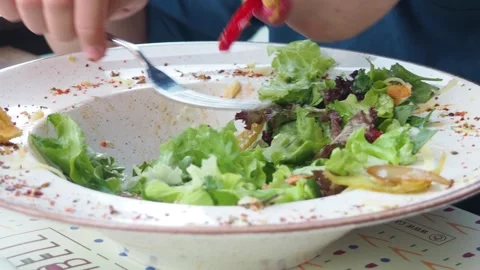 Boy eats healthy lunch of green salad with vegetables and nuts in a cafe Stock Footage 271089974