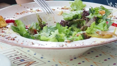 Boy eats healthy lunch of green salad with vegetables and nuts in a cafe Stock Footage 271089976