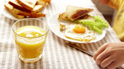 Boy eats his breakfast consisting of a fried egg, some toast and orange juice Stock-Footage 67742194