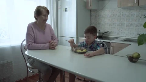 The boy eats on his own in his grandmother's kitchen. Stock Footage 167590933