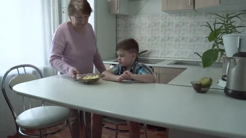 The boy eats on his own in his grandmother's kitchen. Stock Footage 167590934