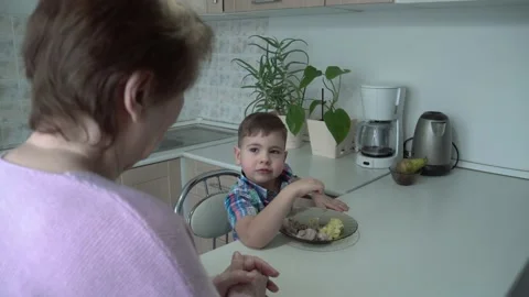 The boy eats on his own in his grandmother's kitchen. Stock Footage 167590937