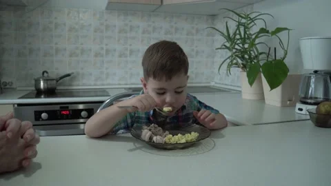 The boy eats on his own in his grandmother's kitchen. Stock Footage 167590941