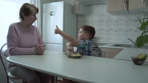 The boy eats on his own in his grandmother's kitchen. Stock Footage 167590942