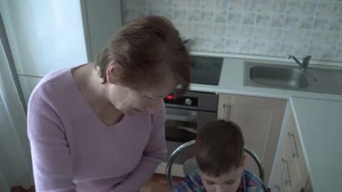 The boy eats on his own in his grandmother's kitchen. Stock Footage 167590943