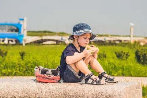 A boy eats his snack on a park bench Stock Photos