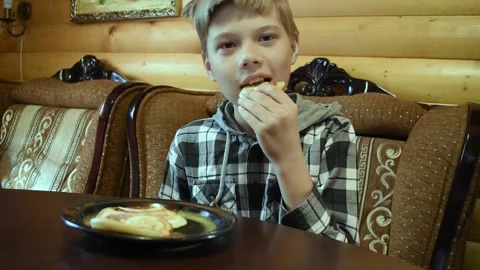 The boy eats homemade delicious pancakes at the table. Stock Footage 132283285