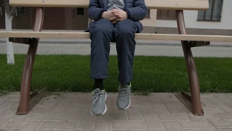 Boy eats Lollipop and shakes her legs on the bench near the house Stock Footage 130117978