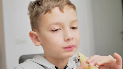 A boy eats pancakes with jam in a white kitchen. close up Stock Footage 228994801